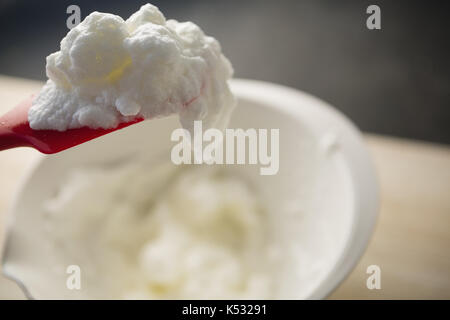 Close up di spatola con la panna montata sulla vaschetta sul tavolo Foto Stock