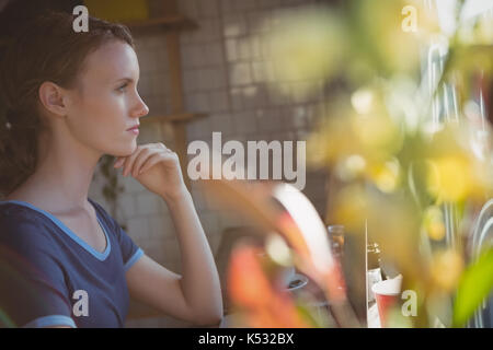 Considerato giovane donna che guarda lontano in cafe Foto Stock