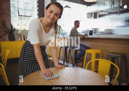 Ritratto di giovane cameriera tabella di pulizia presso il cafe Foto Stock