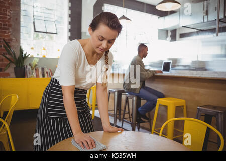 Giovane cameriera tabella di pulizia presso il cafe Foto Stock