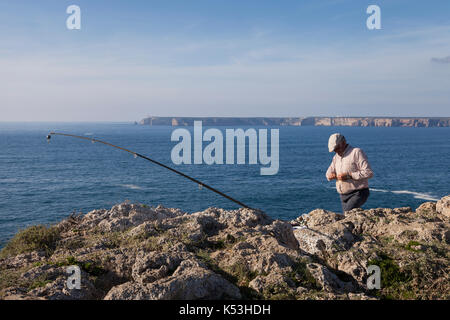 Sagres, Portogallo: Pesca dell'uomo locale a Capo St. Vincent da Sagres Point. Il capo è il punto più sud-occidentale del Portogallo e dell'Europa continentale. Foto Stock