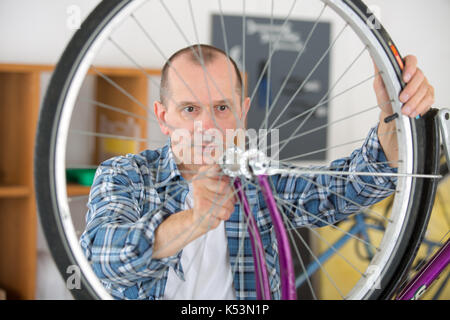 Uomo che fissa cerchio di bicicletta la produzione di ruote Foto Stock