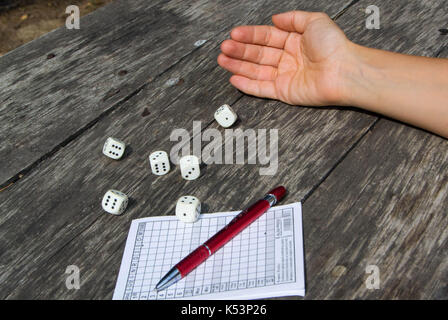 Una donna di mano lancia i dadi e gioca un yahtzee, gioco di dadi Foto Stock