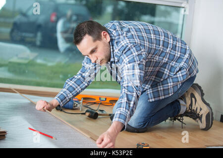 L'uomo la posa di pavimenti in laminato in concetto di costruzione Foto Stock