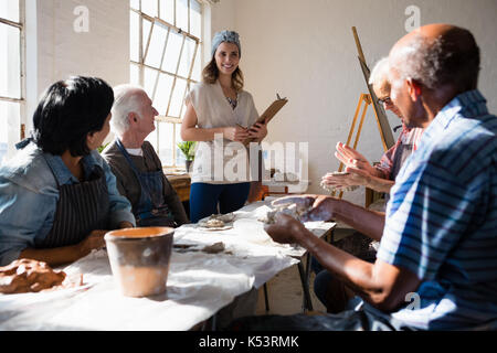 Maestro sorridente guardando senior adulti a tavola in classe d'arte Foto Stock