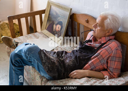 Angolo di alta vista di senior artista maschile rilassante sul divano in classe d'arte Foto Stock