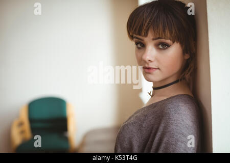 Vista laterale Ritratto di giovane donna dalla parete a casa Foto Stock