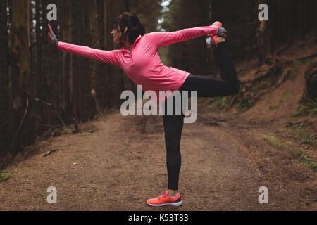 Donna di eseguire esercizi di allungamento in foresta Foto Stock