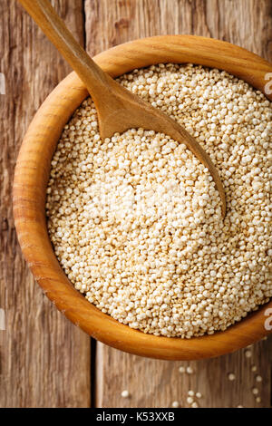 Bianco secco la quinoa in una ciotola di close-up. vista in pianta da sopra lo sfondo verticale Foto Stock