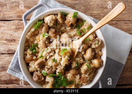 Cibo sano: quinoa con i funghi e le cipolle in una pentola di close-up sul tavolo. vista in pianta da sopra la linea orizzontale Foto Stock