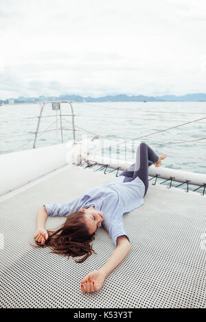 Giovane donna giaceva su una nave da crociera deck durante il viaggio in mare Foto Stock