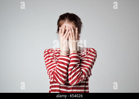 Bella ragazza caucasica si copre la faccia con le mani Foto Stock