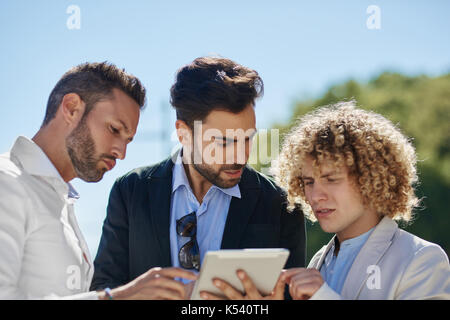 Ritratto di tre uomini di affari utilizzando tablet al di fuori Foto Stock