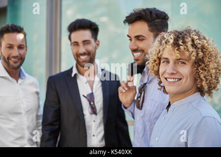 Ritratto di giovane happy businessman in piedi con i colleghi sorridente Foto Stock