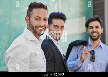 Ritratto di imprenditore bello in piedi con i colleghi sorridente Foto Stock