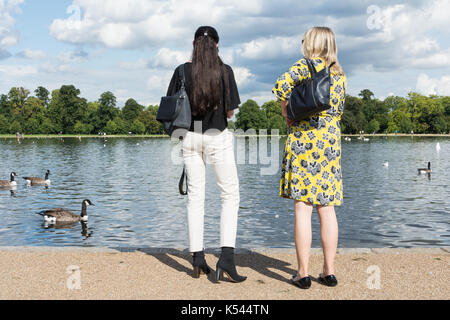 I turisti in piedi accanto al laghetto rotondo, Kensington Gardens, Londra, Regno Unito. Foto Stock