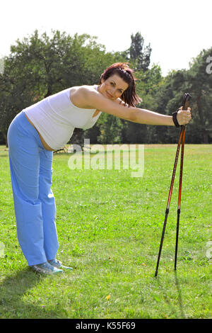 Donna incinta in estate facendo nordic walking Foto Stock