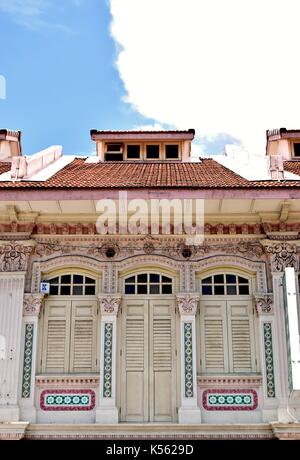 Fila di tre negozi tradizionali esterni della casa bianca con lamelle in legno scuri e finestre ad arco in Joo Chiat quartiere di Singapore Foto Stock