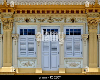 Negozio tradizionale esterno della casa blu con lamelle in legno scuri, facciata gialla, ornato di colonne e sculture di Joo Chiat quartiere di Singapore Foto Stock