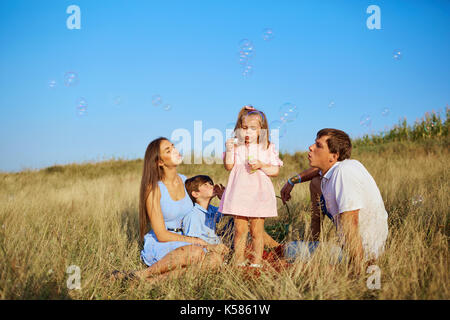 Una famiglia felice sulla natura soffiando bolle di sapone. Foto Stock
