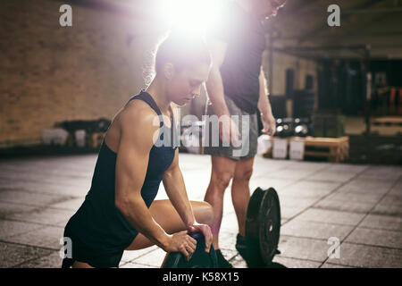 Muscolare di giovane donna e uomo in formazione di abbigliamento sportivo in palestra. Foto Stock