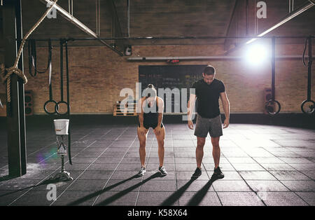 A tutta lunghezza shot di un uomo e di una donna a palestra rilassante dopo allenamento pesante. Foto Stock