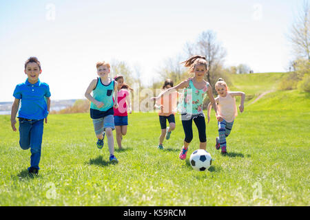 I ragazzi e le ragazze che corre verso il calcio Foto Stock