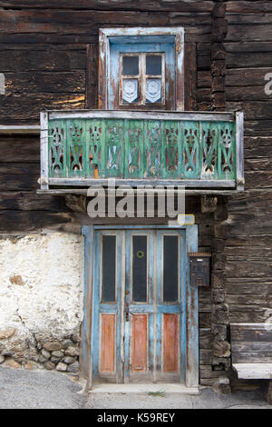 Vecchi rustici di legno porta e finestra in una casa di legno con un piccolo balcone e panca al di fuori Foto Stock