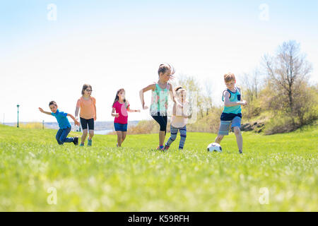 I ragazzi e le ragazze che corre verso il calcio Foto Stock