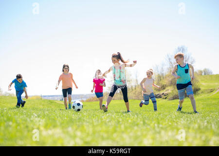 I ragazzi e le ragazze che corre verso il calcio Foto Stock