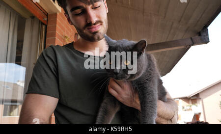 Bel giovane azienda il suo grigio Cat Pet Foto Stock