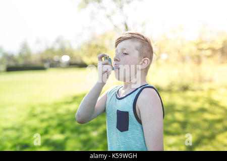 Boy utilizzando un inalatore per asmatici nel parco Foto Stock