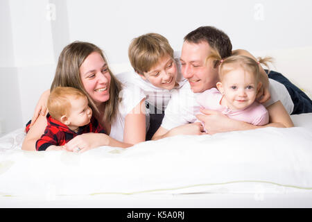 Cinque stati giovane famiglia divertendosi nel letto Foto Stock