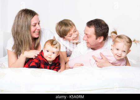 Cinque stati giovane famiglia divertendosi nel letto Foto Stock