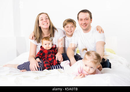 Cinque stati giovane famiglia divertendosi nel letto Foto Stock