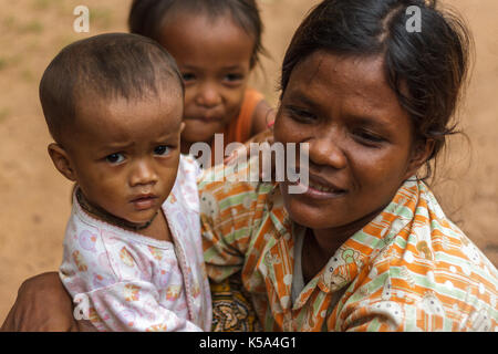 Siem Reap, Cambogia - 9/12/2015: una madre si accovaccia accanto ai suoi figli in un villaggio. Foto Stock