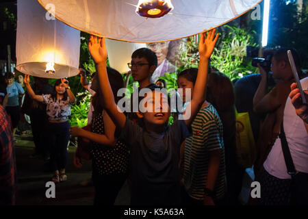 Chiang Mai, Thailandia - 12/30/2015: un giovane ragazzo rilascia una lanterna oscillante a un tempio per la vigilia di capodanno in Chiang Mai, Thailandia. Foto Stock