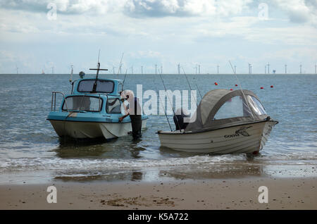 Uomo con piccole barche da pesca a Clacton-on-Sea, England, Regno Unito Foto Stock