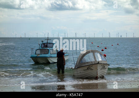 Uomo con piccole barche da pesca a Clacton-on-Sea, England, Regno Unito Foto Stock