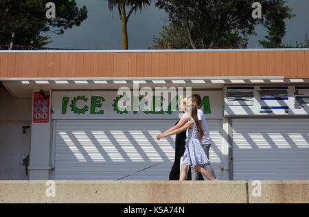 La gente camminare passato chiuso gelateria sul lungomare a Clacton-on-Sea, England, Regno Unito Foto Stock