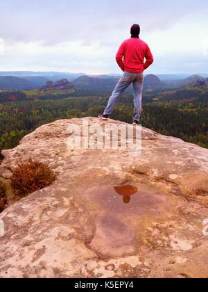 Escursionista l uomo rimane su un costone roccioso e godono di vista sulla valle lunga all'orizzonte. a freddo sun nascosti nelle nuvole. parco nazionale con una montagne rocciose e val Foto Stock