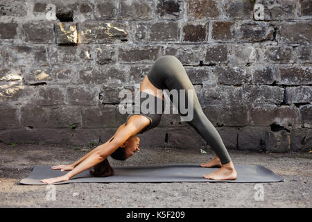 La donna a praticare yoga contro un muro di mattoni Foto Stock