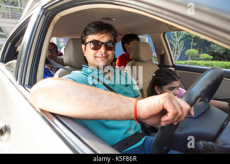 Padre indiano e i bambini seduti nuova guida auto prestito bancario Foto Stock