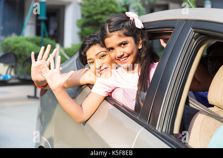 Madre e figlia piccola seduta auto lasciando le mani gesticolando bye bye felice viaggio Foto Stock