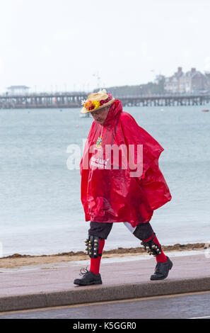 Swanage, Dorset, Regno Unito. 9 Sep, 2017. Regno Unito meteo: heavy rain e tuoni a Swanage. Morris uomo che indossa rosso poncho impermeabile passeggiate lungo la promenade. Credito: Carolyn Jenkins/Alamy Live News Foto Stock