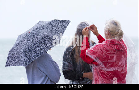 Swanage, Dorset, Regno Unito. 9 Sep, 2017. Regno Unito meteo: heavy rain e tuoni a Swanage. 3 persone che cercano di mantenere asciutto, riparando sotto ombrellone o indossando ponchos. Credito: Carolyn Jenkins/Alamy Live News Foto Stock