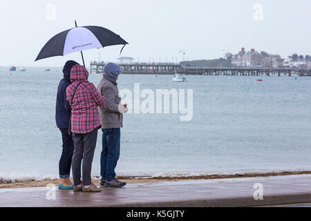 Swanage, Dorset, Regno Unito. 9 Sep, 2017. Regno Unito meteo: heavy rain e tuoni a Swanage. Tre persone riparo sotto ombrellone cercando di tenere a secco con Swanage Pier nella distanza. Credito: Carolyn Jenkins/Alamy Live News Foto Stock