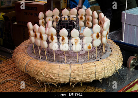 Tokyo, Giappone - dango, un snack giapponese, tre riso cake palle su uno spiedino arrosto e riscaldata vicino ad una stufa a carbone Foto Stock