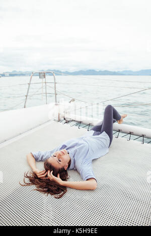 Giovane donna giacciono su una nave mentre godendo di una crociera su uno yacht Foto Stock