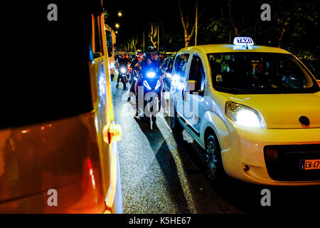 Gli autobus, automobili e motociclette e scooters lotta per lo spazio durante il traffico di notte ad Atene, Roma il 23 settembre 2017. Foto Stock